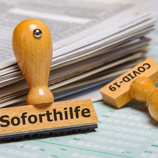 Zwei Stempel die auf Unterlagen liegen, auf dem einen steht Soforthilfe und auf dem anderen Covid-19